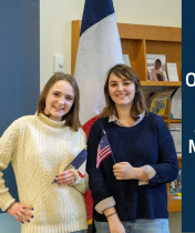 A picture of Eliana Ondrejko and Jeanne  Mocellin standing in front of a French flag, each holding a flag from their home country. Jeanne is holding the French flag and Eliana is holding the American flag.