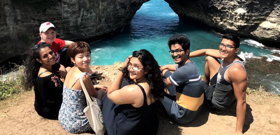 A group of CWRU study abroad students sitting together on a hill over looking water