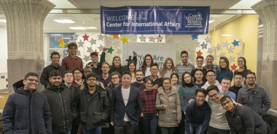 A group of CWRU international students stand in front of a #YouAreWelcomeHereCWRU sign