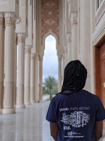 A female CWRU student stands with her back turned to the camera wearing a CWRU study abroad tee shirt