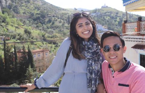 Two students stand outside in front of a hillside while studying abroad