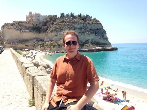 A CWRU student sits on a beachfront in Italy