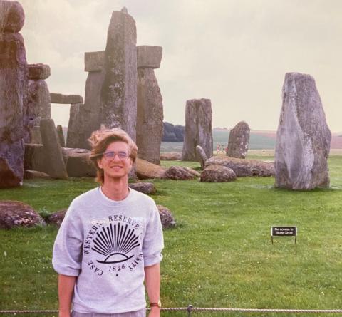A CWRU student in a CWRU sweatshirt stands in front of Stonehenge