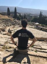 A picture of Michel Yuzik sitting with his back facing the camera, wearing a #YouAreWelcomeHereCWRU shirt during his study abroad