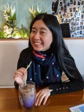 A headshot of Fei Wang smiling at a restaurant