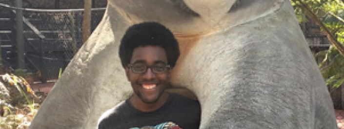 A photo of Miles Booker standing with a statue of a koala bear