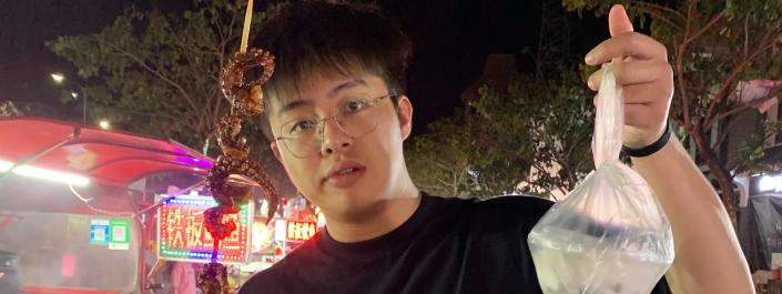 Zeyuan Zhan holding a skewer of food