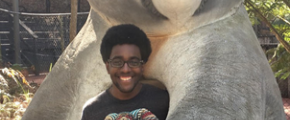 A photo of Miles Booker standing with a statue of a koala bear