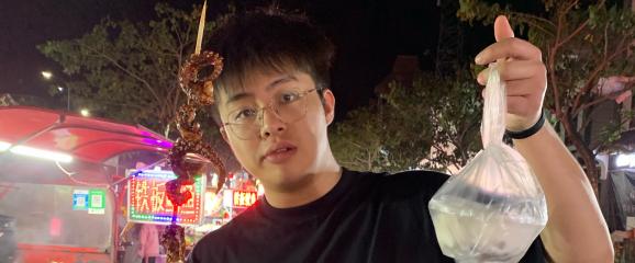 Zeyuan Zhan holding a skewer of food