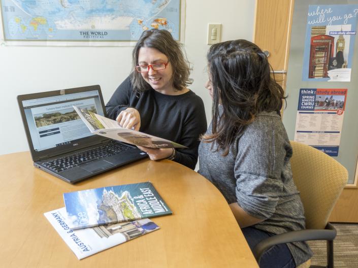 Study Abroad Advisor Cami Ross meets with a student about study abroad opportunities and shows the student a brochure about available opportunities.