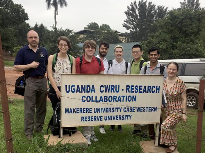 CWRU faculty and students stand near a sign that reads: "Uganda CWRU-Research Collaboration Makerere University Case Western Reserve University"