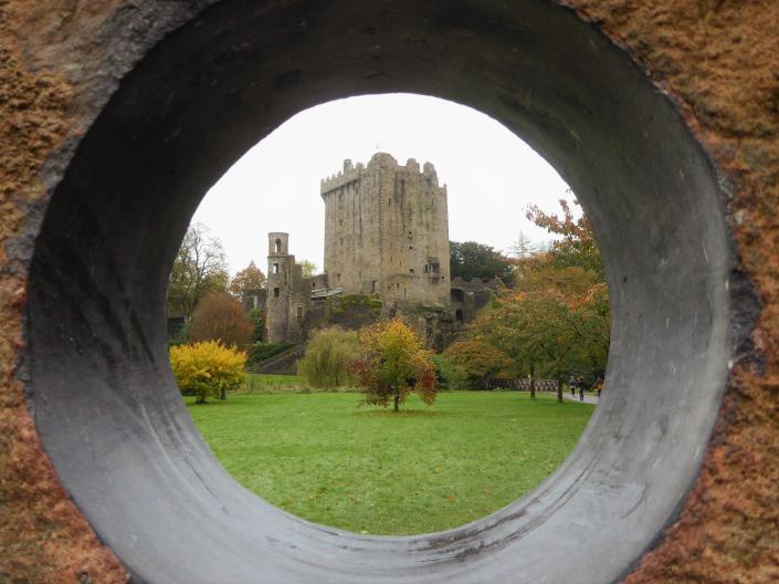 A picture taken through a circular hole in a wall showing a building through it
