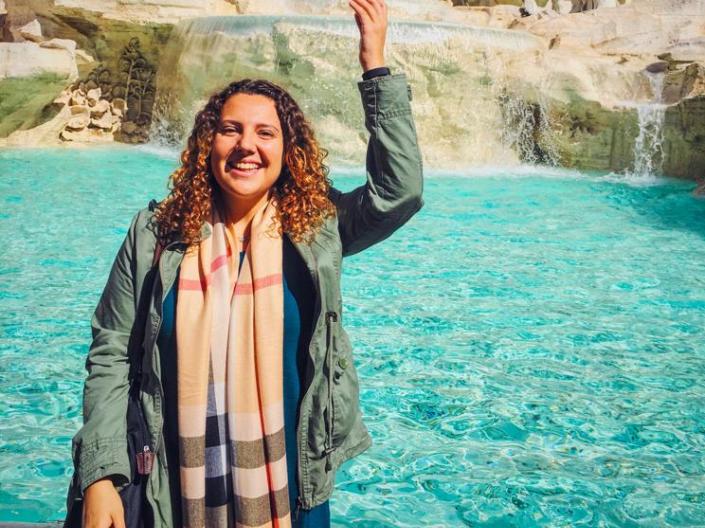 A student throws a coin into a fountain while studying abroad