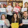 Staff holding up signs that say You Are Welcome Here in multiple languages
