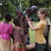 CWRU student kneels as Ugandan child looks through camera and other children look on