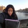 Girl reads from notebook with Amsterdam canal in the background