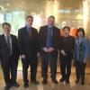 Small group of representatives from CWRU and TMU pose in front of a decorative water wall