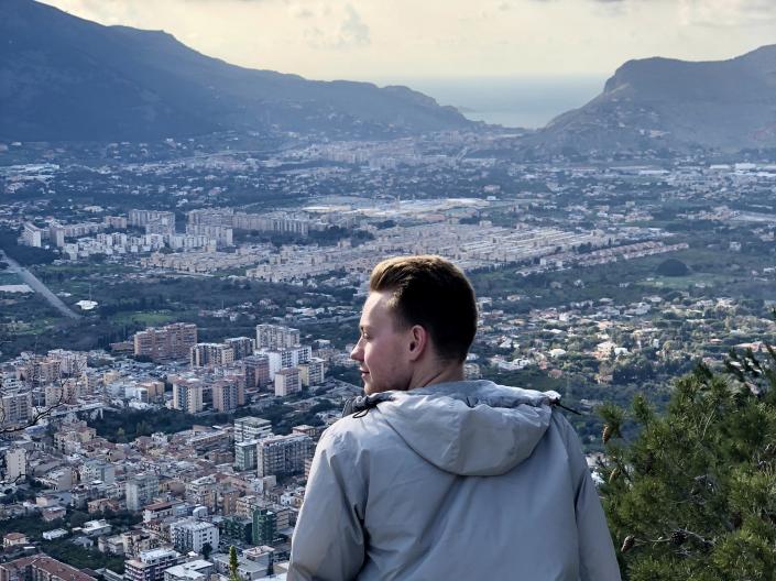 Jack Webb sitting on a hill overlooking a city during his study abroad