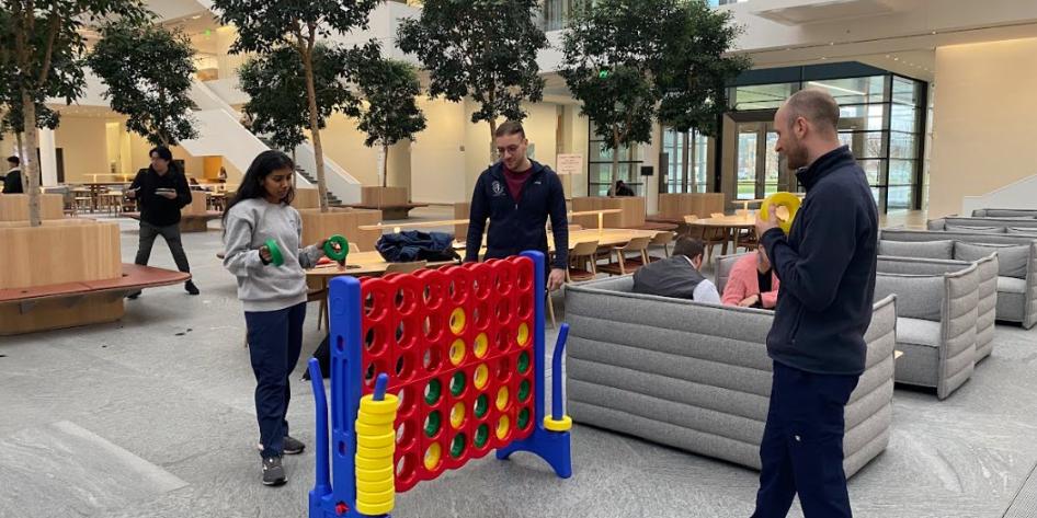 A photo of 3 students playing a large connect four game