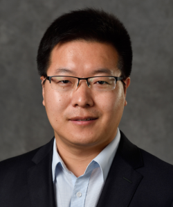 Dr. Cao headshot smiling slightly in dark blue blazer and open-necked light blue button-down shirt