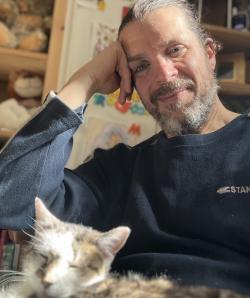 Dr. Bendik-Keymer seated and smiling with a cat in his lap