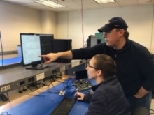 Instructor pointing to computer screen as female student looks on
