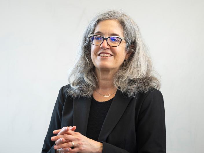 A smiling law professor in a black blazer engaged in conversation, representing the school's commitment to faculty-student interaction.