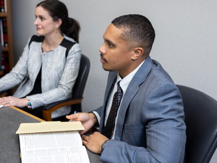 Law students reviewing legal materials and cases during a research session in a law library or conference room.