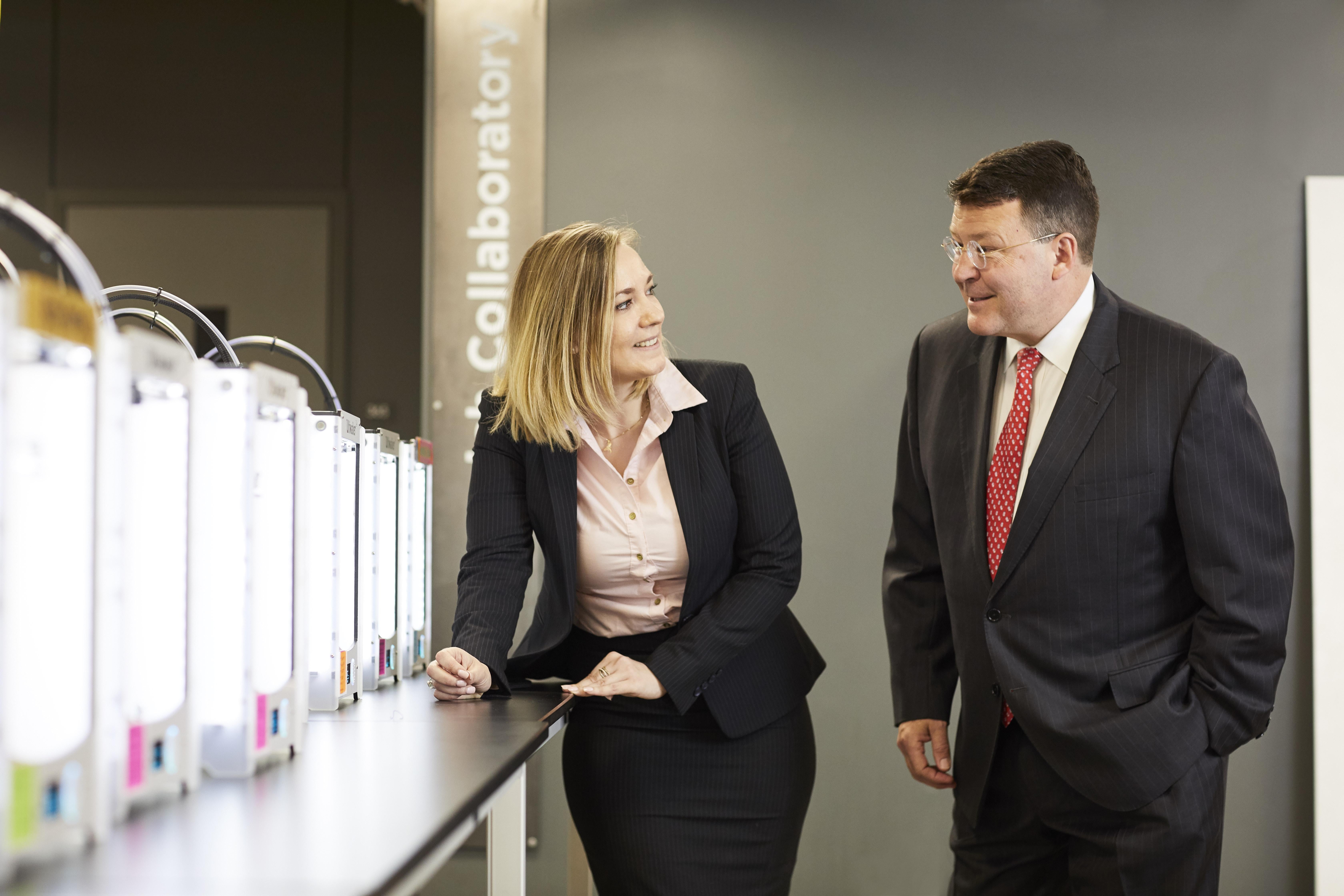 Student Rebecca Lindhorst and Professor Ted Theofrastous speak near a set of 3D printers.