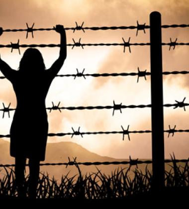 Woman holding onto a barbed wire fence