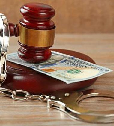 Image of a gavel handcuffs overtop of money