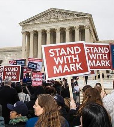 Image of protestors outside capital building with signs that say "Stand With Mark"