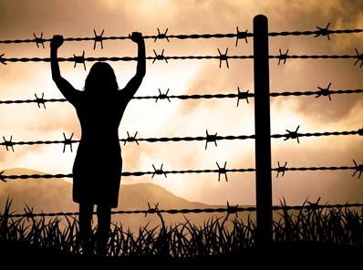 Woman holding onto a barbed wire fence