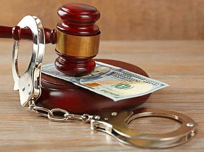 Image of a gavel handcuffs overtop of money