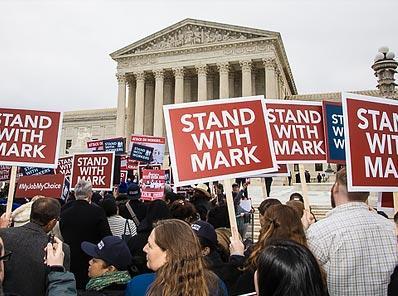 Image of protestors outside capital building with signs that say "Stand With Mark"