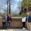 Three students and their professor in front of Gund Hall Case Western Reserve School of Law sign