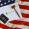 U.S. Passport and gavel atop a U.S. Citizenship and Immigration Services Plaque with an American Flag background