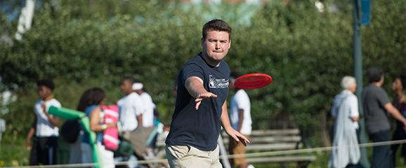 college student thowing a frisbee in a grassy area