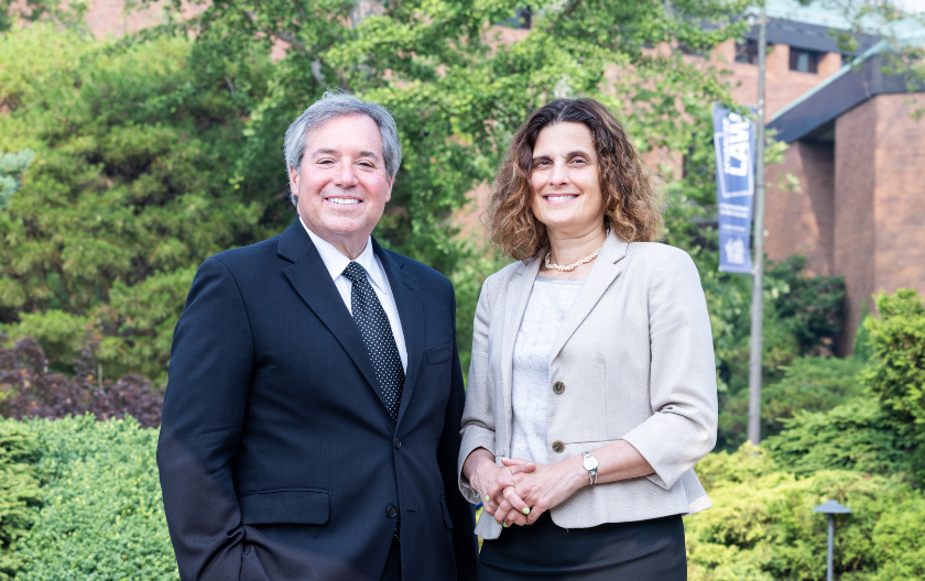 Michael Scharf and Jessica Berg pictured outdoors in front of the law school building