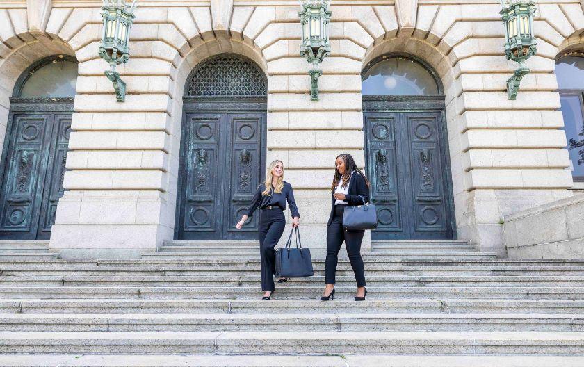 Two students walking down stairs in business attire. 