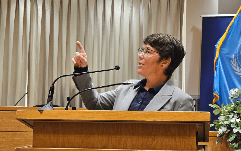 Kati Kovacs presenting in the Moot Courtroom, standing behind the podium and gesturing with her right hand.