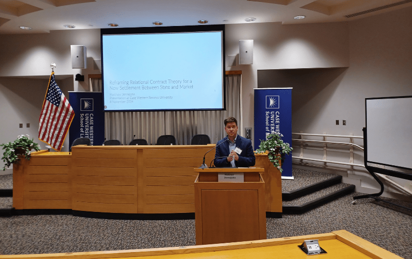 A speaker stands behind the podium during his presentation, addressing the audience