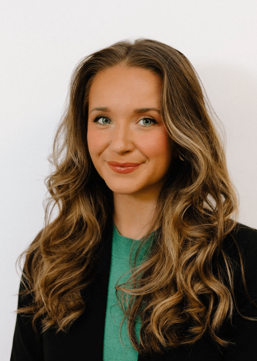 Caroline Smith Headshot, wearing a green blouse under a black blazer