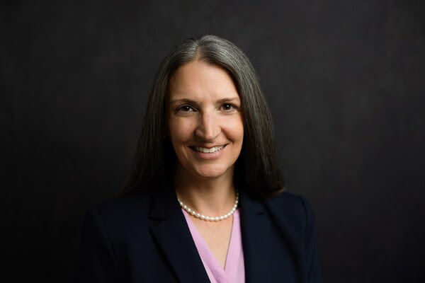 Colleen Batcheler headshot in front of dark grey background