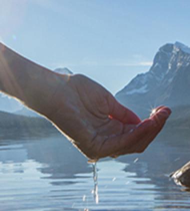 Photo of a hand reaching into a lake