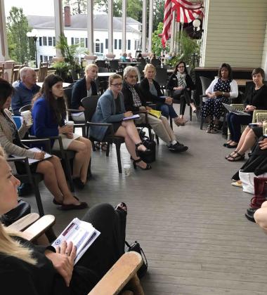 Chautauqua roundtable event in 2023, attendees gather on a porch to listen to panelists discuss 