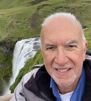 A selfie of Dr. Stuart Bussey, taken in front of green fields and a waterfall