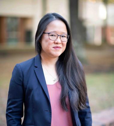 Cathy Hwang headshot, wearing a black blazer and a pink blouse