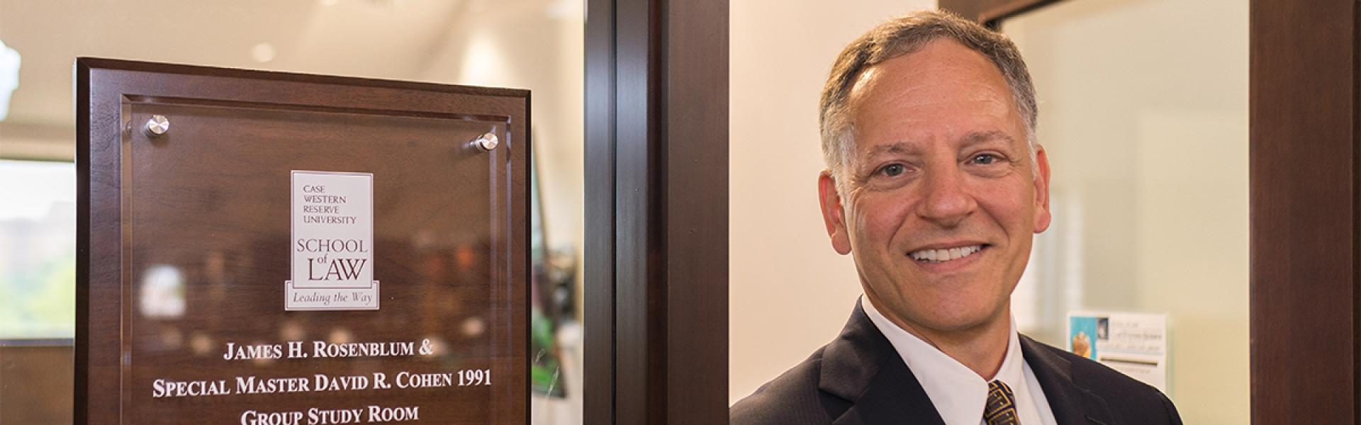 David Cohen in front of a plaque in the Law School