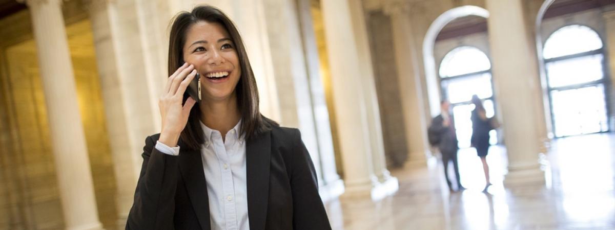 law student smiling on cell phone in lobby of large building